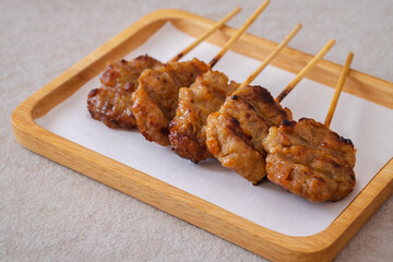 Barbecue pork or grilled pork skewer on wooden plate, Thai street food