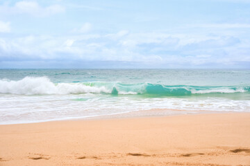 Beautiful blue green aqua waves of the Pacific ocean as it breaks onto beach 