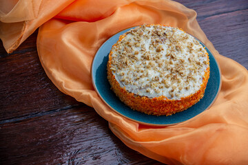 Delicious carrot cake with orange color organza cloth on wooden background