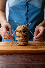 Close up of woman tying the rope knot on a pile of biscuits and chocolate cookies on a brown on kitchen table