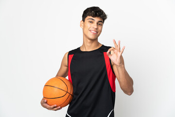 Young man over isolated white background playing basketball and making OK sign