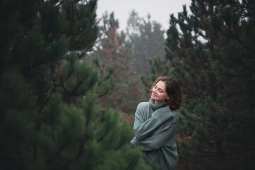 Young beautiful happy woman walking in fir forest enjoying nature meditating outdoors