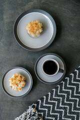 Delicious homemade carrot cupcakes or muffins with cup of coffee on minimalist stone background and geometric fabric cloth