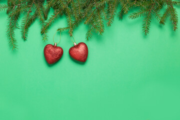 Two hearts on a green background with fir branches, Christmas toys. Valentine's Day holiday. A heart donor . Places to copy space