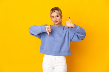 Young Russian woman isolated on yellow background making good-bad sign. Undecided between yes or not © luismolinero