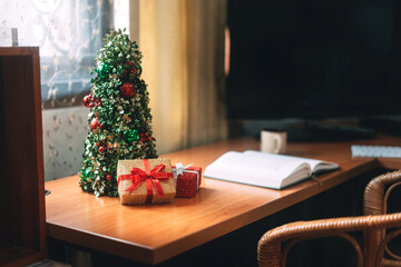 Christmas tree and wapped present boxing decorated at home office with laptop computer.