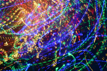 Bright multicolored Christmas lights shot on long exposure in motion against a black background. a...