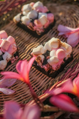 Rocky road brownies with colorful marshmallows on wooden plate with pink flowers