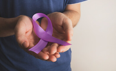 Man holding lavender color awareness ribbon. World cancer day, epilepsy. Medicine and healthcare...