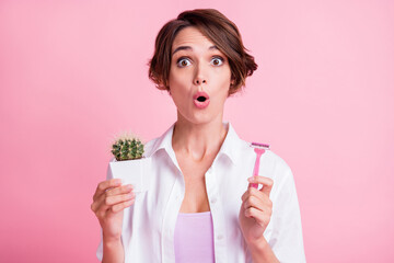 Portrait of attractive impressed lady hold cactus razor open mouth isolated on pink color background