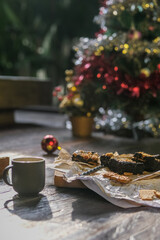 Christmas cakes and cookies on wooden table by festive decorated fir tree