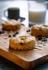 Oatmeal cookies with raisins on rustic wooden chopping board background with glass of milk