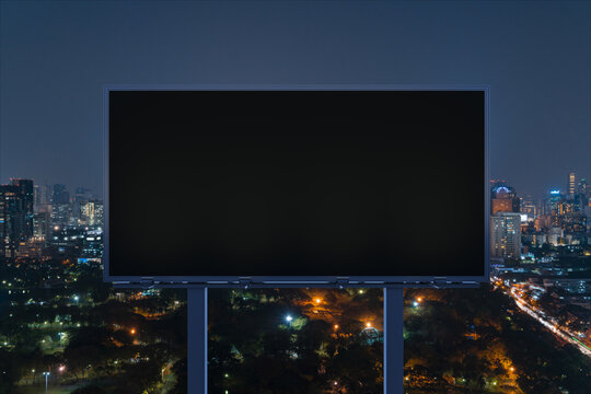 Blank black road billboard with Bangkok cityscape background at night time. Street advertising poster, mock up, 3D rendering. Front view. The concept of marketing communication to sell idea.