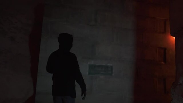 Young protester in black hood and mask uses a flaming molotov's cocktail, he throws it in a wall. Dangerous using flaming mixes on streets protest 