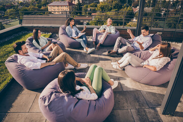 Nice attractive stylish partners leaders company unity sitting in bag chairs discussing project development on roof outside outdoor sunny day