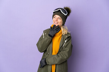Skier Russian girl with snowboarding glasses isolated on purple background looking up while smiling