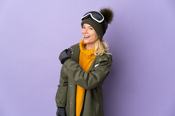 Skier Russian girl with snowboarding glasses isolated on purple background celebrating a victory