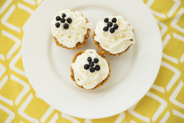 Homemade muffins with blueberries, cream and fresh berries on a yellow napkin