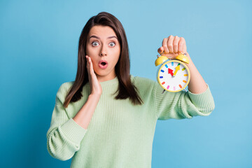Photo of astonished girl touch hand face hold clock isolated over blue color background