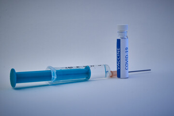 Close up of a vial with vaccine and a syringe on a white background. Close up of a flask with...