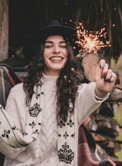 A woman of model appearance with curly long dark hair in a sweater hat and a winter scarf holds a...