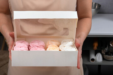 Woman holds gift box with handmade multicolored marshmallows. Confectioner