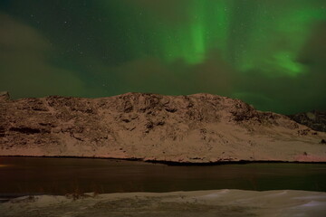 Fototapeta na wymiar Aurora borealis Green northern lights above mountains