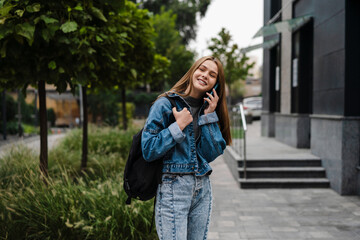 Beautiful happy student girl smiling and talking on mobile phone