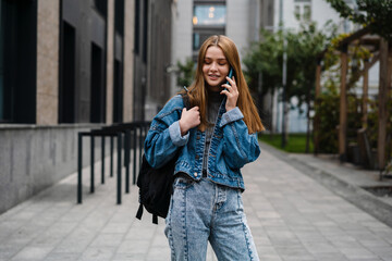 Fototapeta premium Beautiful happy student girl smiling and talking on mobile phone
