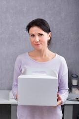 Woman is holding white cardboard box. Packaging for cakes and pastries. Vertical frame