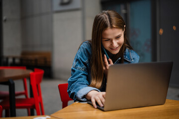 Beautiful happy girl talking on cellphone while working with laptop