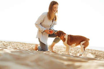 Woman playing with dog outside at the beach