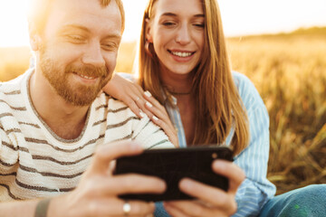 Happy positive loving couple using mobile phone