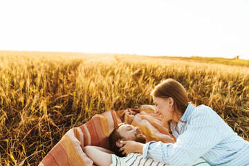 Loving couple lying together outside at the field