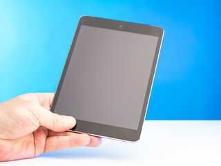 A man's hand with a tablet computer. Electronic tablet with a clean screen. The man looks the information in the tablet. A person demonstrates an electronic gadget.