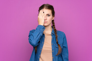 Young woman over isolated purple background covering a eye by hand