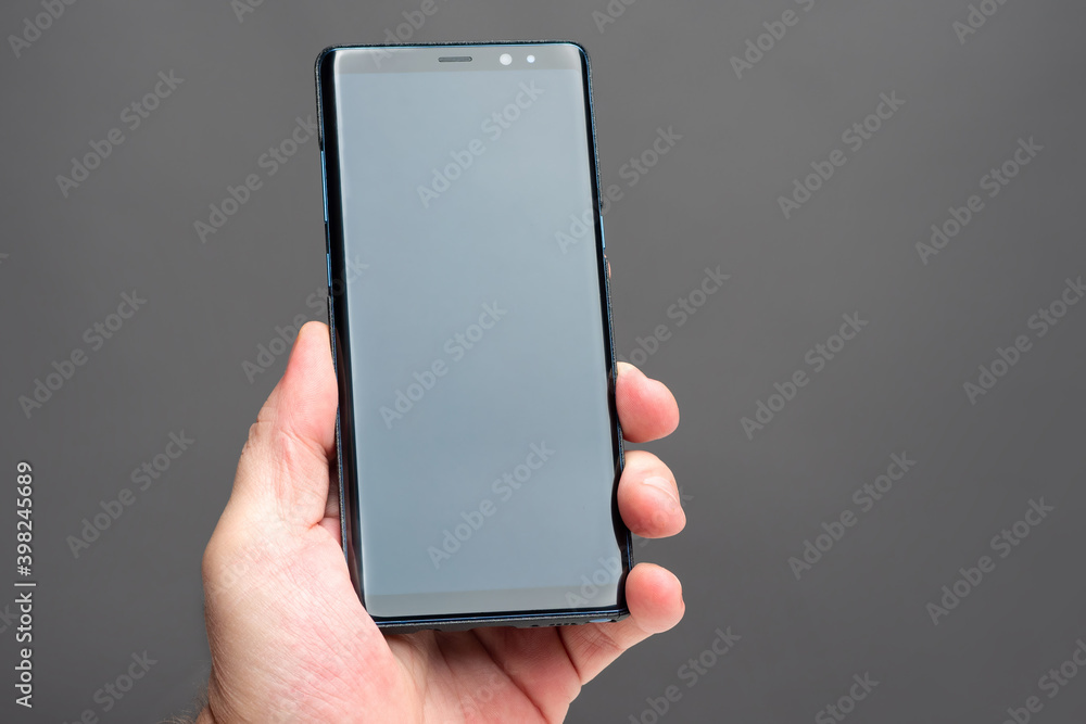 Poster man hand with a smartphone. a man holds a mobile phone vertically. a smartphone with a blank screen 