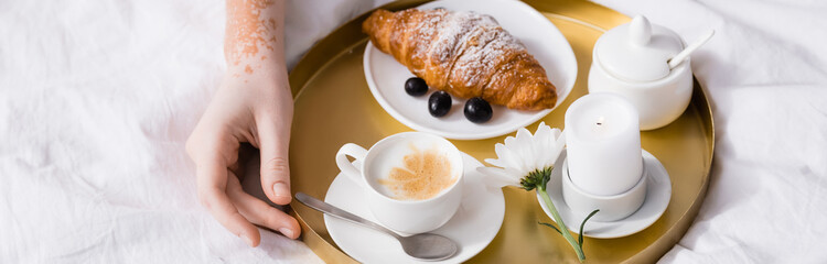 partial view of woman with vitiligo touching tray with breakfast, banner
