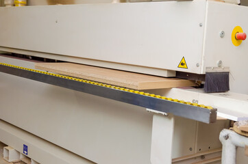 Close-up of a part of a wooden part on an edge-banding machine. Woodworking machine in a carpenter's workshop