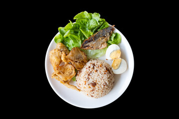 Spicy fried rice with crispy mackerel, mushroom, green oak lettuce and egg on black background. Popular hot and spicy Thai food in white plate.