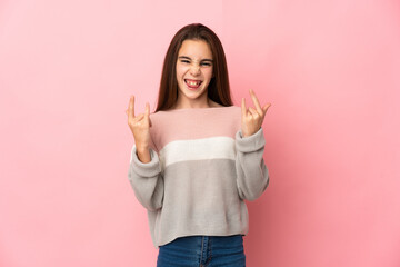 Little girl isolated on pink background making horn gesture