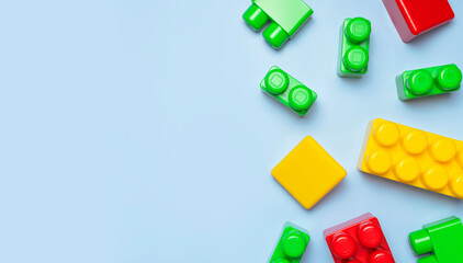 Multicolored plastic kids constructor on blue background. Colored children's bricks for construction. Flat lay top view copy space. Plastic building blocks background. Developing toys, game