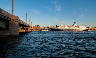Big sea ship on the English Embankment in front of the Blagoveshchensky drawbridge. Black water of the Bolshaya Neva river. St Petersburg, Russia.
