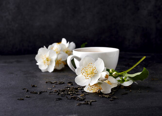 Fototapeta na wymiar Jasmine flowers and cup of healthy tea on a black background. Herbal medicine
