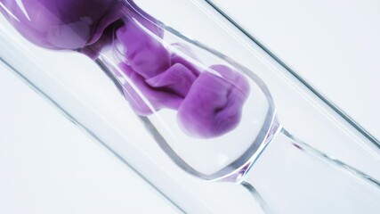 Pink liquid substance flows through a glass flask. Concept for advertising perfume and cosmetic products. Mixing pink ink with water in a large laboratory glass test tube. Close up.
