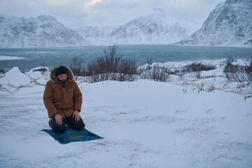 Muslim traveler praying in cold snowy winter day