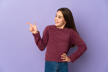 Little girl isolated on purple background pointing finger to the side and presenting a product