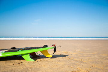 Cropped surfboard or longboard lying on sand beach. Blue sky and ocean or sea waves with foam on background. Selective focus. Surfing, extreme sport and summer vacation concept