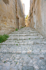 Fototapeta na wymiar Small street with cobblestone stairs in Unesco town Matera, Italy