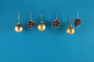 golden christmas balls and fir-cones isolated on blue background. Christmas decoration concept